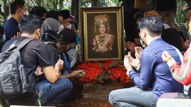 Keluarga berdoa di atas pusara Artis Dorce Gamalama usai dimakamkan di TPU Bantar Jati, Cipayung, Jakarta Timur, Rabu (16/2/2022). [Azarphesha.com/Alfian Winanto]