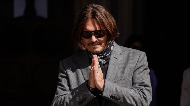 Aktor Johnny Depp memberi salam saat tiba di Pengadilan Tinggi di London, Britain, Senin (20/7/2020).   [Niklas HALLE'N / AFP]